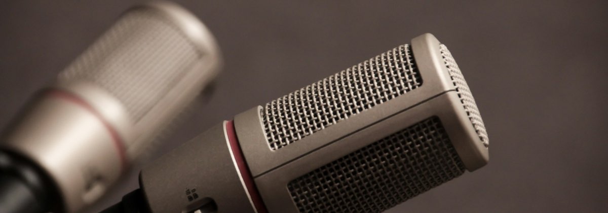 Two podcast microphones facing each other across a table