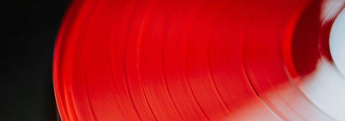 Turntable playing a red vinyl record, showing how slowing playback speed lowers a song's pitch